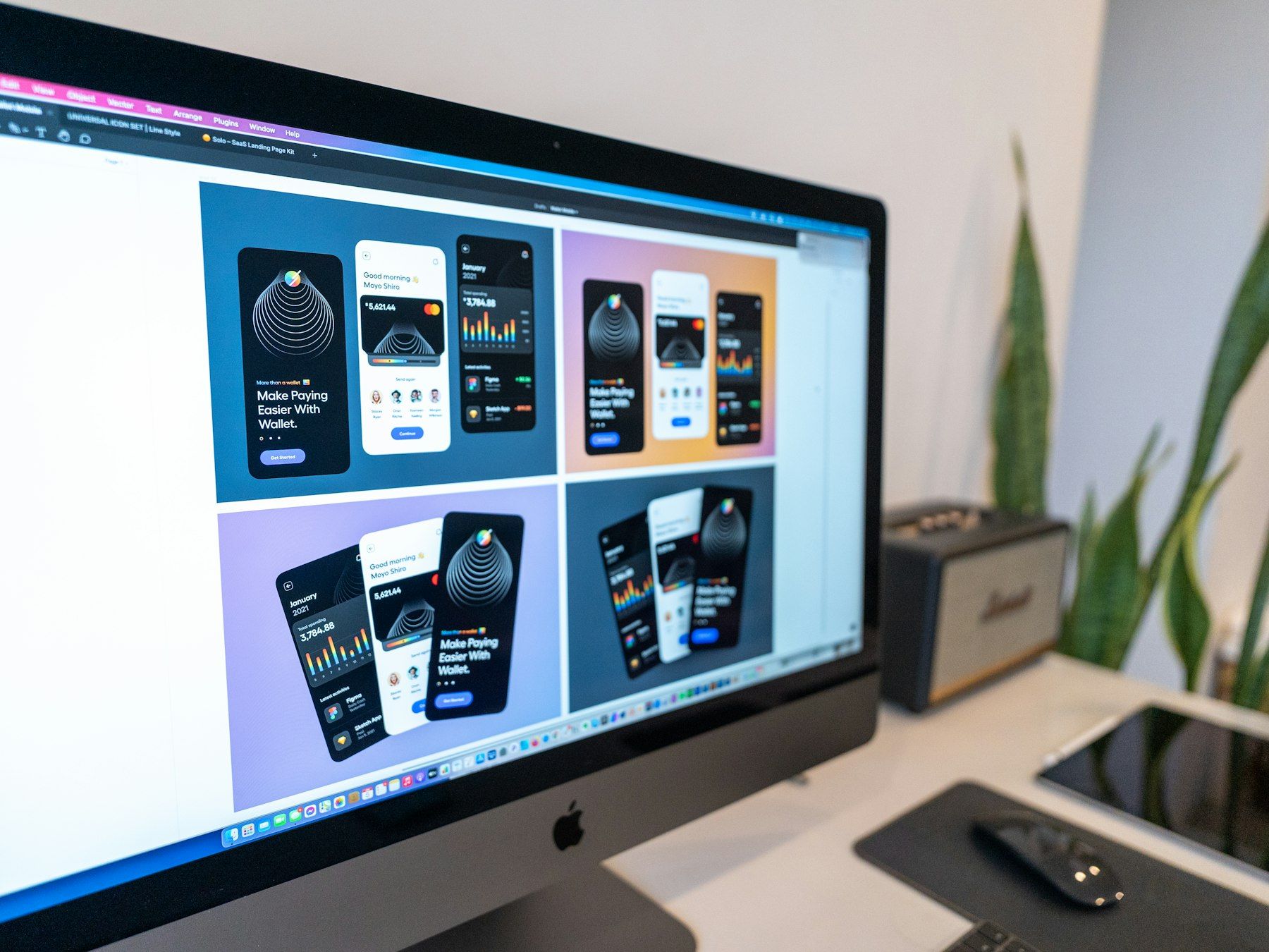 Desktop monitor on a white desk showing app interface designs in a design tool
